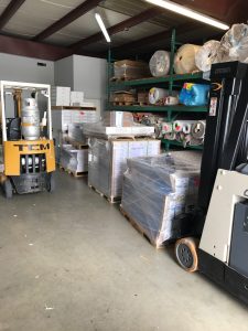 A warehouse with rack of carpets, and crates of stock.